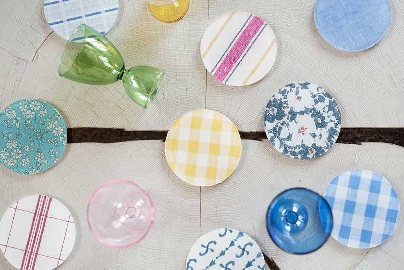 Colorful ceramic coasters with different patterns arranged on a textured surface.