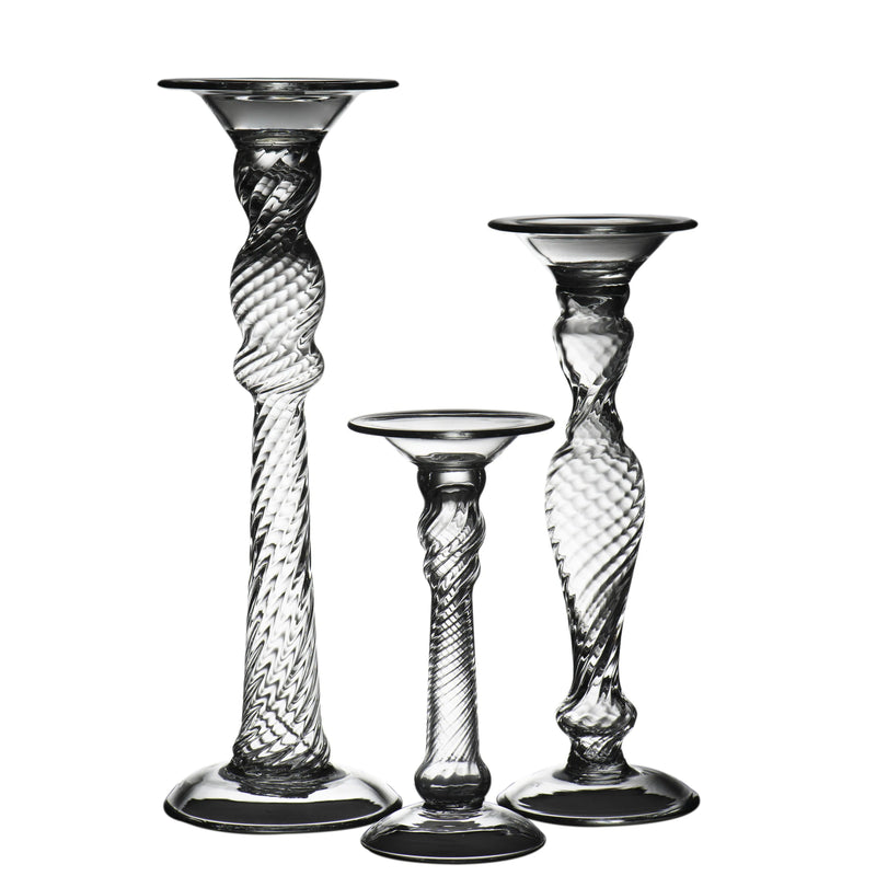 Set of three glass candle holders with twisted design on a white background