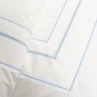 Close up of white duvet cover with blue embroidery