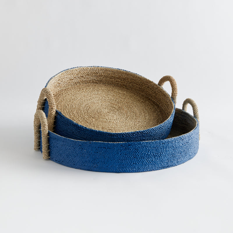 Two seagrass basket trays with blue outside on white background.